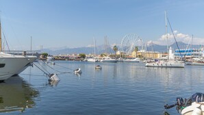 A marina with multiple boats docked, a Ferris wheel, and a mountainous backdrop. - Beautiful home in Corsanico (Corsanico)