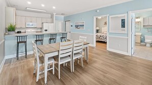 A modern kitchen with white cabinets, a central island, and bar stools.