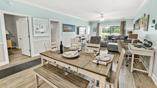 A dining area with a wooden table set for four, a sofa, and a desk with a lamp.
