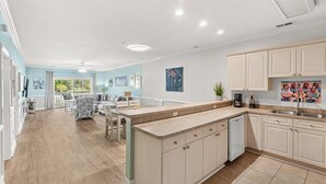 A spacious kitchen with light-colored cabinets, a central island, and a dining area with a patterned sofa.