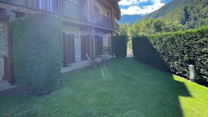 Un bâtiment à deux étages doté d’un balcon, entouré d’une pelouse bien entretenue et d’une haie.