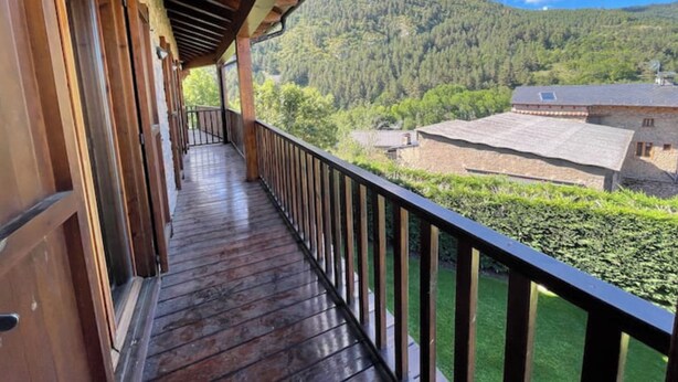 Un balcon en bois offrant une vue sur une montagne et un bâtiment.
