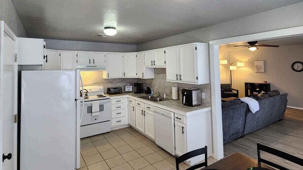 Una cocina compacta con armarios blancos, un refrigerador y un comedor con mesa y sillas.
