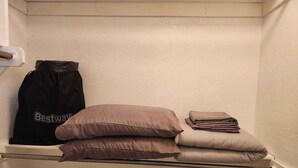 Un área de almacenamiento con una barra de metal, una bolsa negra con la etiqueta 'Bestway' y varios almohadones doblados.