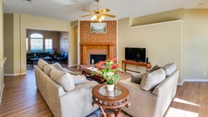 A spacious living room with a fireplace, two sofas, a coffee table, and a TV.