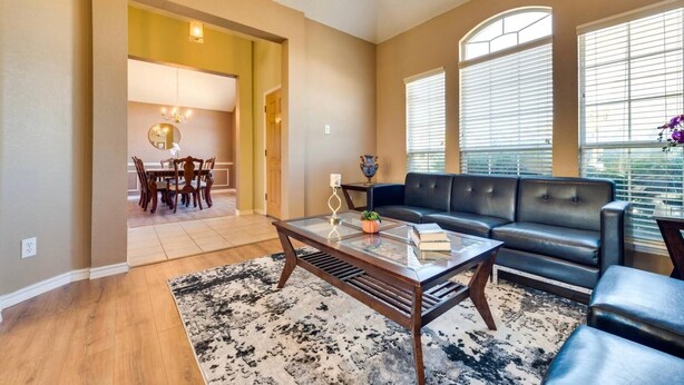A living room with a sofa, a coffee table, and a dining area with a table and chairs.