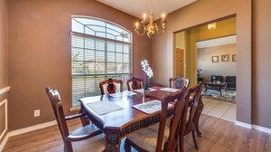 A dining room with a large table, six chairs, and a chandelier.