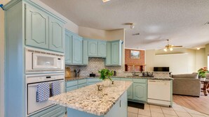A kitchen with light blue cabinets, a granite countertop, a microwave, an oven, and a dishwasher.