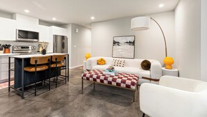 A modern kitchen with a dining area, white furniture, and a large window. - 2BR/2BA in the Heart of Ballard (Seattle)
