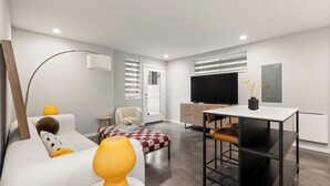 A modern living room with a sofa, a coffee table, a TV, and a dining area with a table and chairs. - 2BR/2BA in the Heart of Ballard (Seattle)