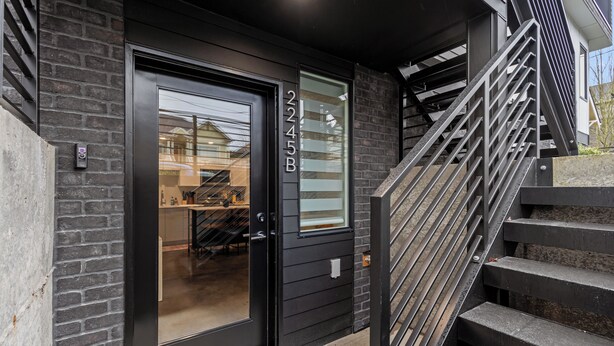 A modern building entrance with a black door, a glass window, and a staircase leading up. - 2BR/2BA in the Heart of Ballard (Seattle)