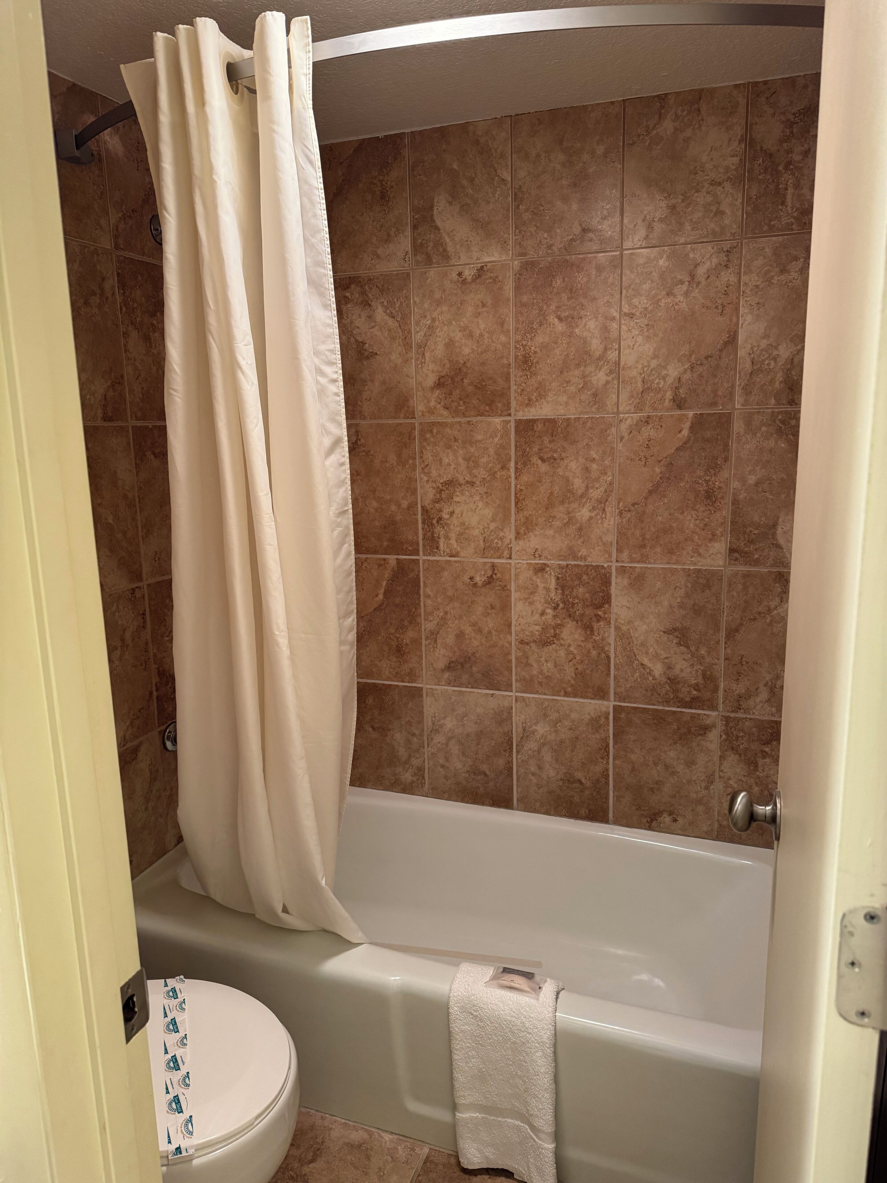 Une salle de bain avec une baignoire, des toilettes et un rideau de douche.