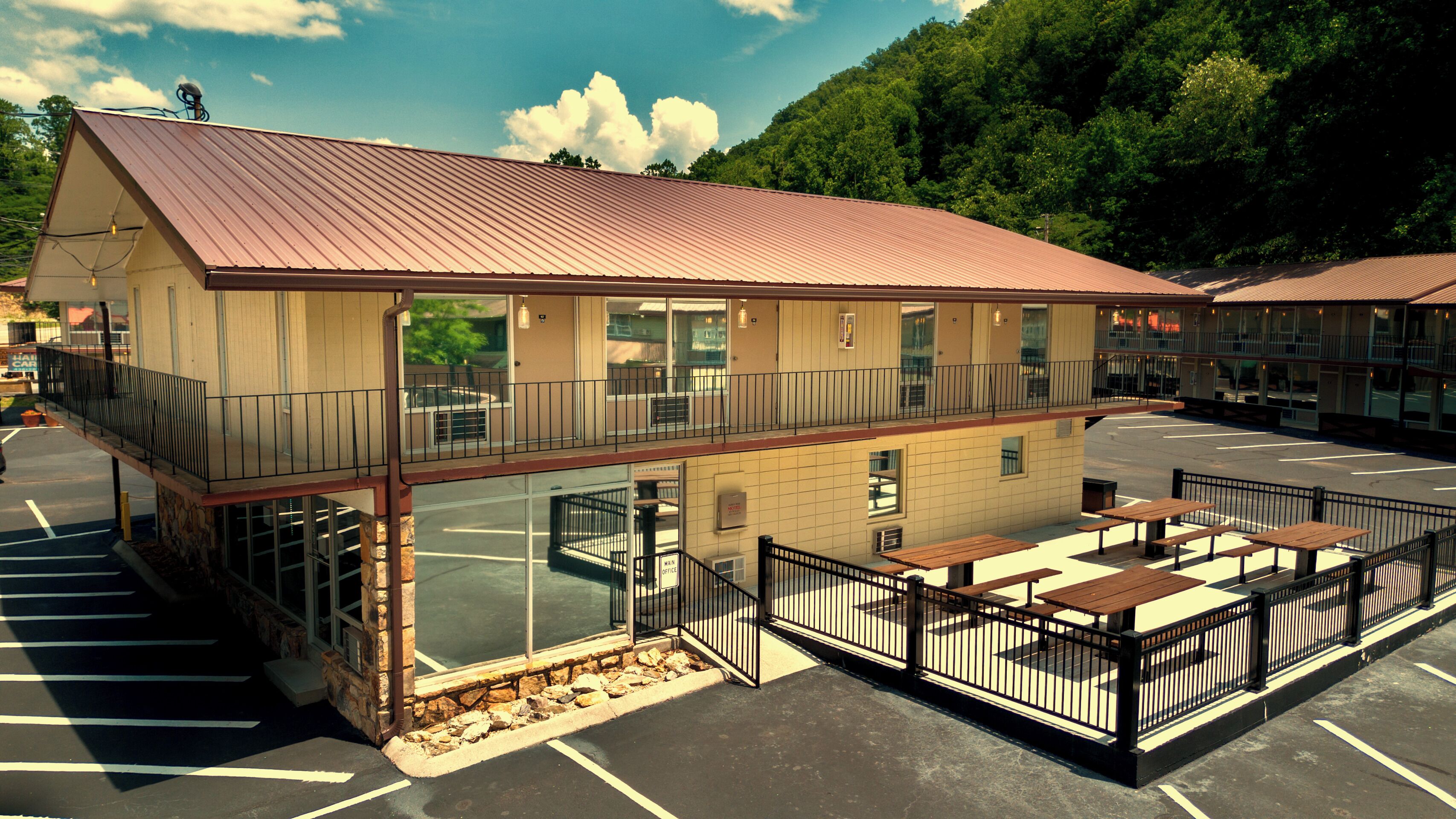 A two-story building with a metal roof, large windows, and a parking lot.