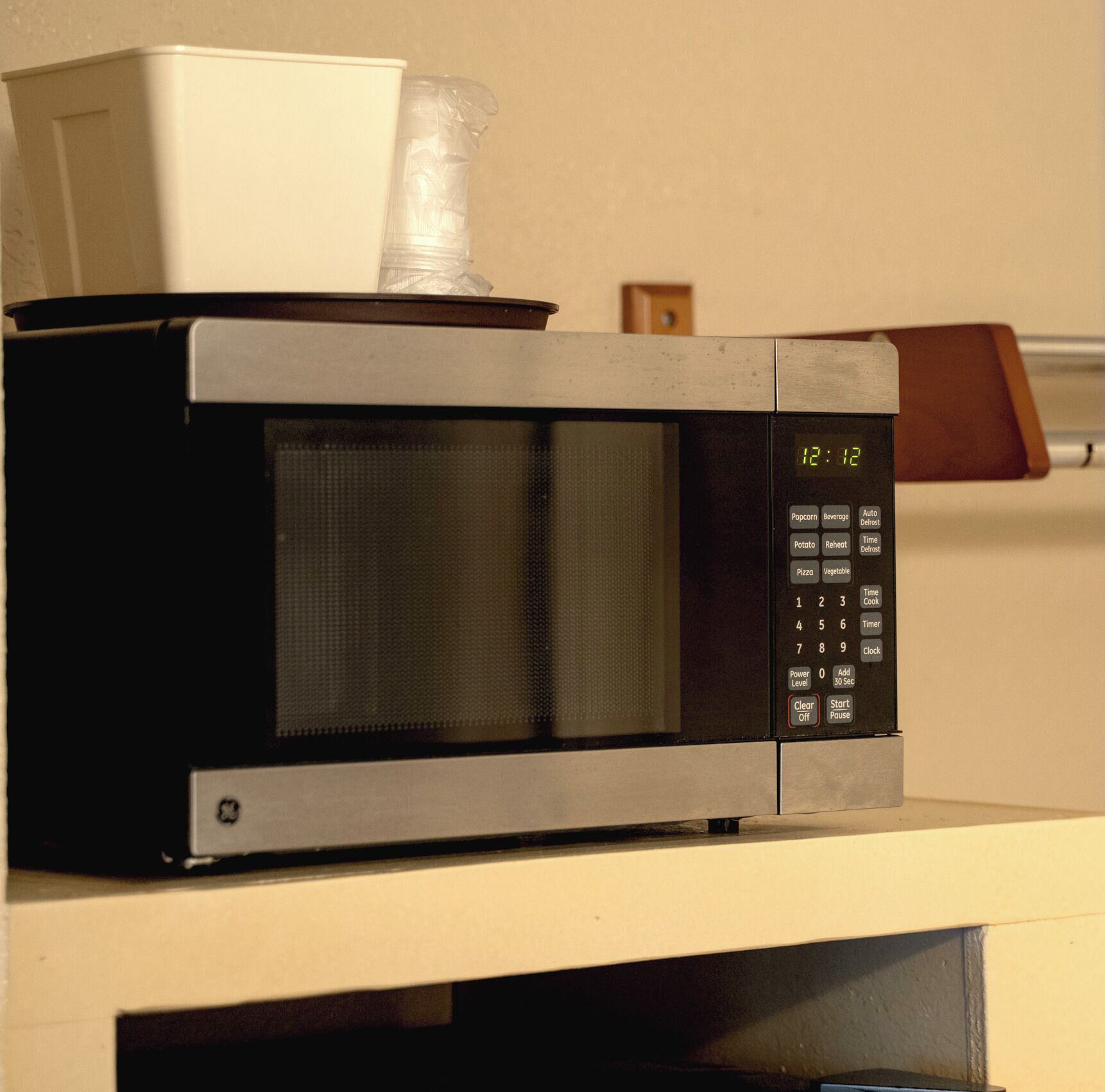 A microwave oven with a digital display, control panel, and a plastic bag on top.