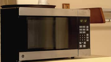 A microwave oven with a digital display, control panel, and a plastic bag on top.