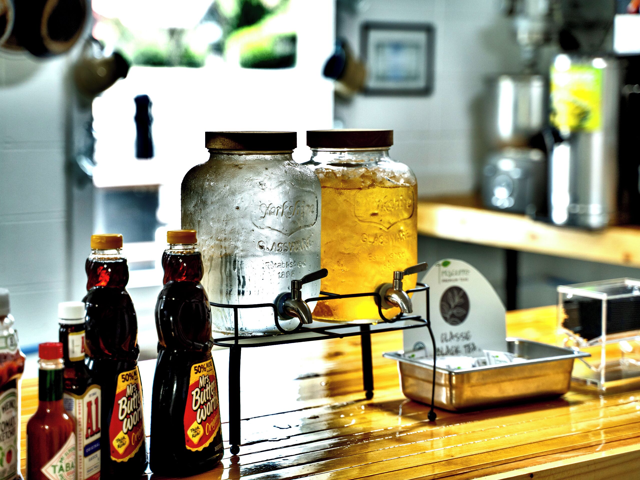 A bar area with a tap, bottles, and a large glass jar.