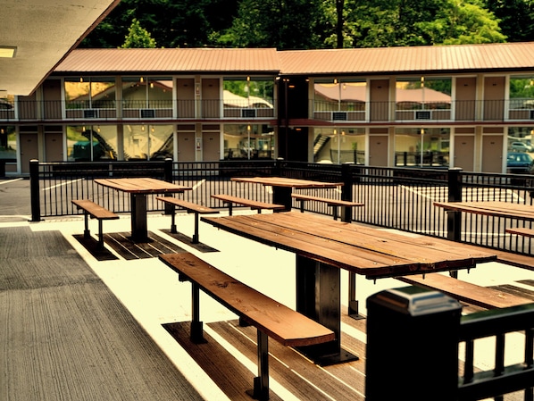 Outdoor picnic tables arranged in rows with a building in the background. - Sleepy Bear Motel (Gatlinburg)