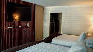A hotel room with two beds, a wooden panel wall, a television, and a wardrobe. - Sleepy Bear Motel (Gatlinburg)
