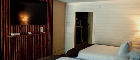 Una habitación de hotel con dos camas, un panel de madera, un televisor y un armario.