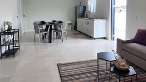 A spacious living area with a dining table, chairs, a sofa, and a kitchen in the background. - Casa Tuturutu (Willemstad)