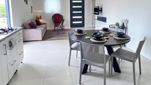 A modern kitchen with a dining area, white cabinetry, and a large window. - Casa Tuturutu (Willemstad)