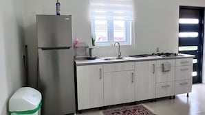 A kitchen with a refrigerator, sink, and cabinets. - Casa Tuturutu (Willemstad)