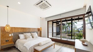 A modern bedroom with a large bed, wooden headboard, and a balcony with a view of palm trees. - Luxury Beachside Condo in Hacienda Pinilla-Steps from Sand! Beach Club access (Tamarindo)