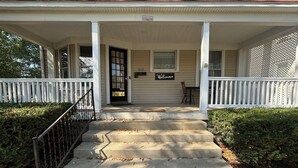 A two-story house with a front porch, a welcome sign, and a mailbox.