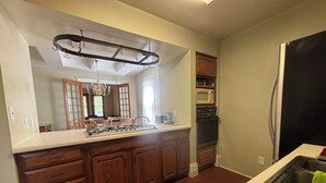 A kitchen with wooden cabinets, a gas stove, a microwave, and a refrigerator.