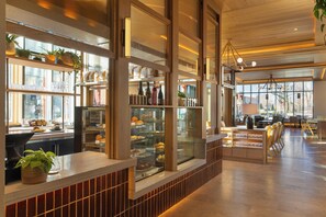 A modern interior with a counter, display cases, and seating area. - The Compton (Bentonville)