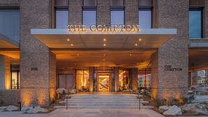 A hotel entrance with a brick facade, illuminated signage, and a staircase leading to the entrance. - The Compton (Bentonville)