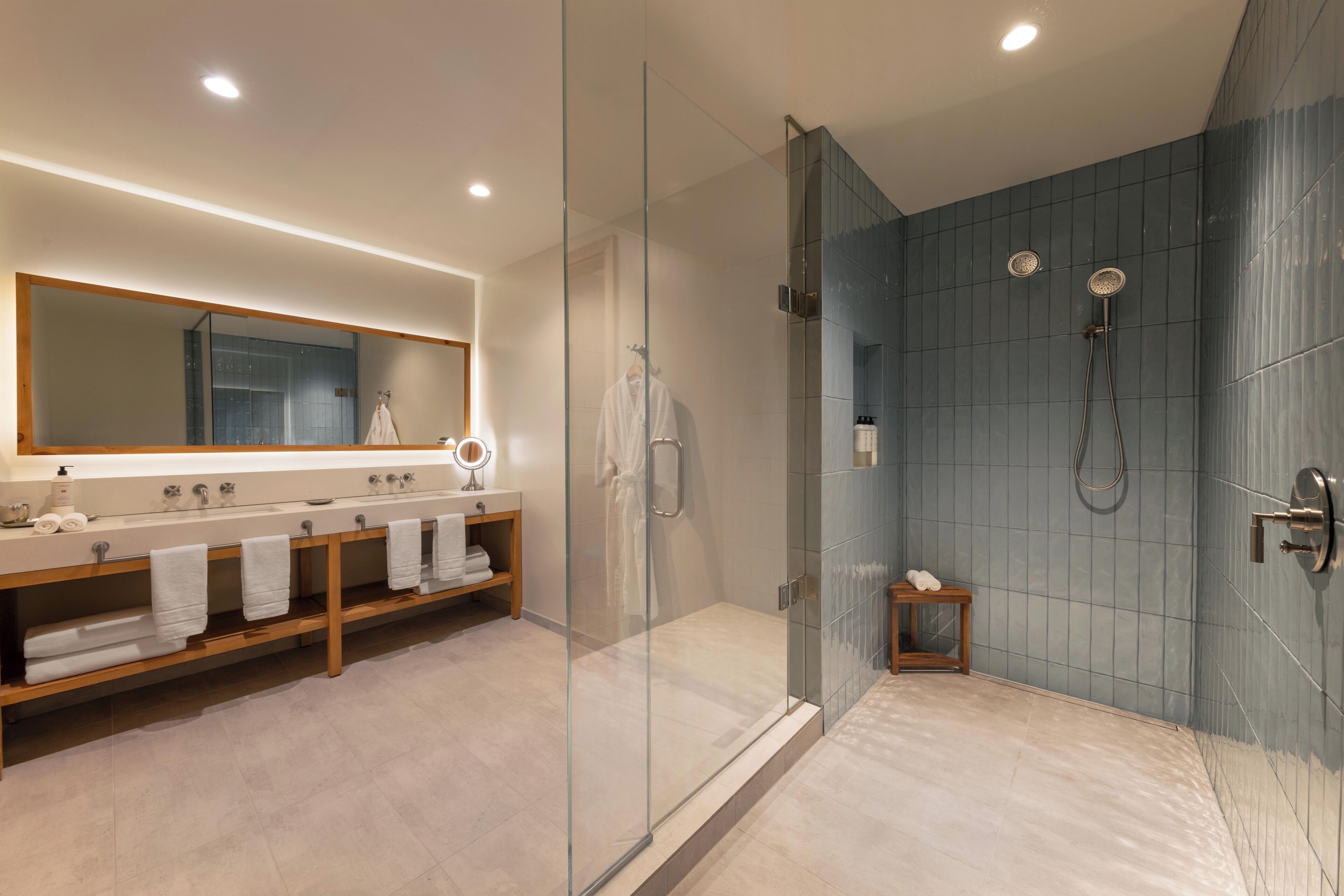 A modern bathroom with a glass-enclosed shower, a vanity with a mirror, and multiple towels.