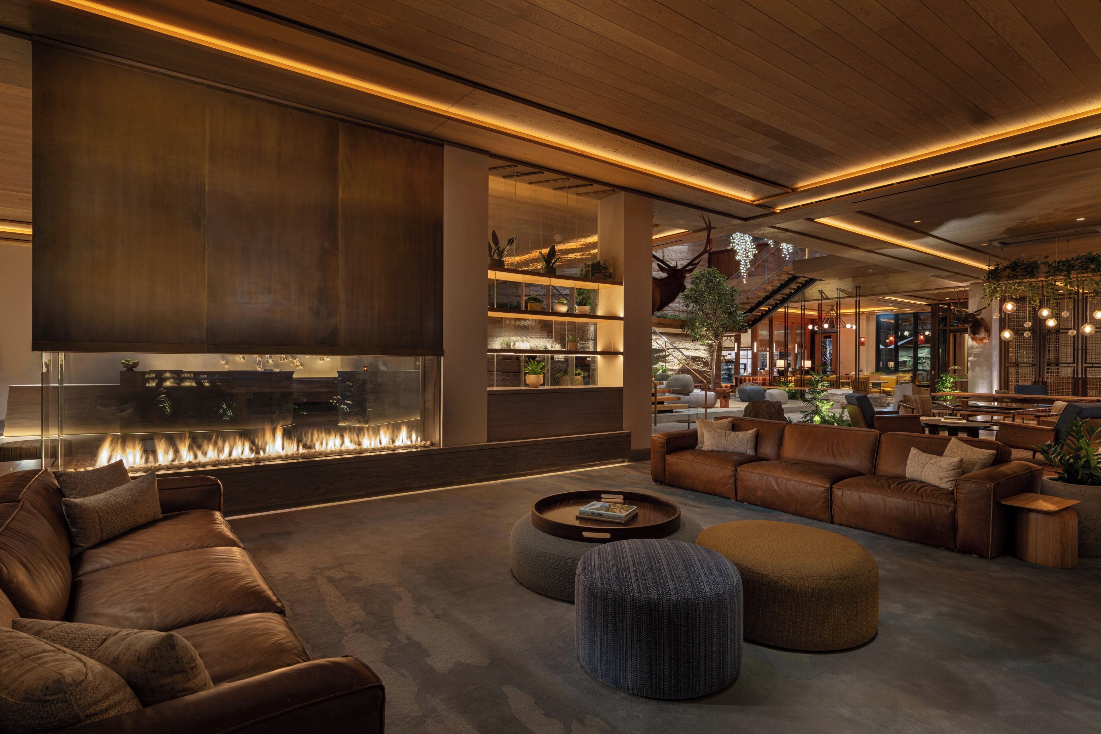 A modern interior with a fireplace, leather sofas, and a wooden ceiling.