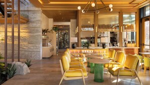 A modern interior with a bar area, seating, and a stone wall. - The Compton (Bentonville)