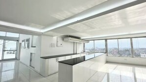 A modern kitchen with a central island, large windows, and a city view. - 250 sq.ft 3 Studio Apartment w/ Pool & Private Sauna (Dhaka)