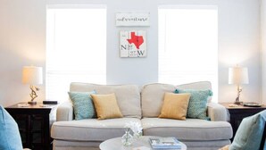 Un salon avec un canapé, deux lampes et un mur orné d’une carte et d’une affiche sur laquelle on peut lire le mot « aventure ».