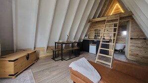 Un dormitorio acogedor en el ático con una cama de madera tipo entrepiso, una kitchenette pequeña y un baño.