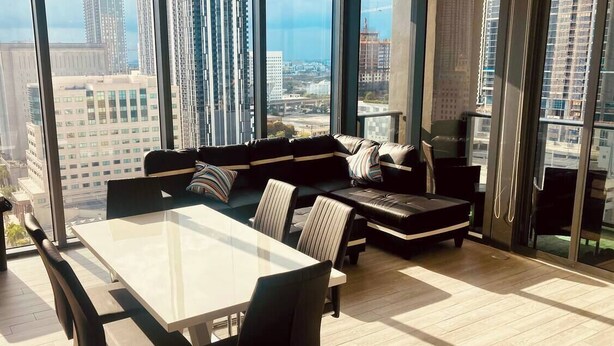 A modern living room with a large glass window, a dining table, and a sofa set. - Miami downtown Amazing view rooftop pool & jacuzzi (Miami)