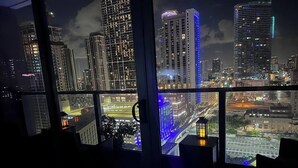 A view from a high-rise hotel room with large windows overlooking a cityscape at night. - Miami downtown Amazing view rooftop pool & jacuzzi (Miami)