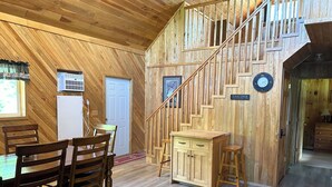 A wooden interior with a dining area, a staircase, and a small kitchen.