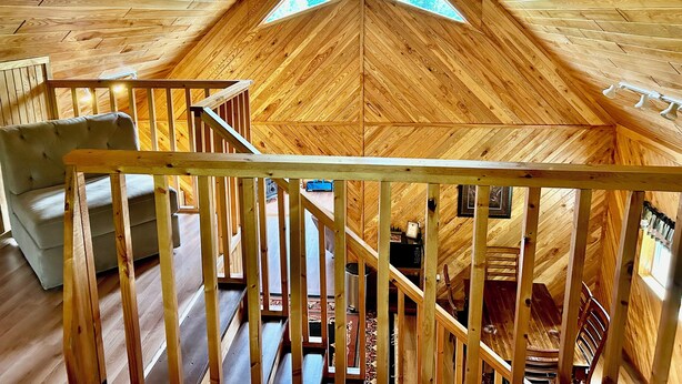 A wooden interior with a high ceiling and a central skylight.