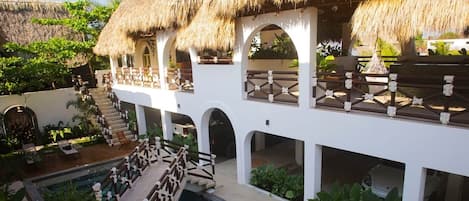 A resort with a pool, thatched-roof structures, and a covered outdoor area.