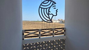 Un balcone con tetto di paglia, una recinzione con motivi geometrici e un'ampia opera d'arte a parete raffigurante il profilo di una donna.