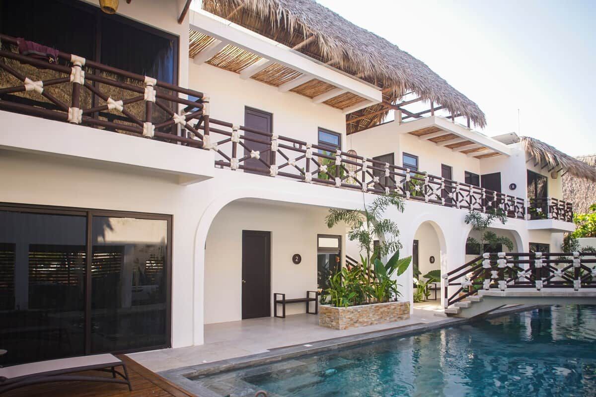 Un resort con piscina, varios balcones y techo de paja.