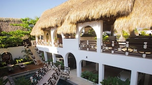 Un resort con piscina, strutture a tetto di paglia e una zona esterna coperta con posti a sedere.