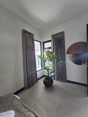Una habitación con un ventanal grande, una planta en maceta y un adorno en la pared.