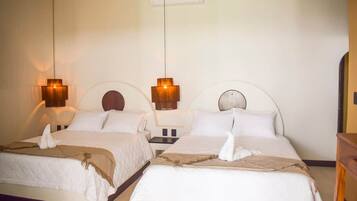 Habitación de hotel con dos camas, cada una con cabecera, mesita de noche y lámpara colgante.