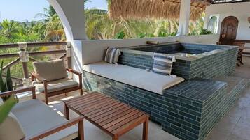 Een terras op het dak met een hottub, zitgedeelte en uitzicht op palmbomen.
