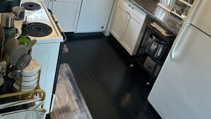 A kitchen with white cabinets, a stove, a microwave, and a refrigerator.