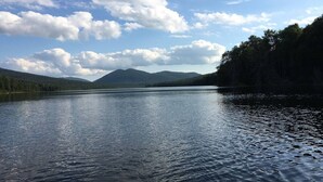 Un lac paisible, avec des montagnes en arrière-plan et une zone boisée sur la droite.
